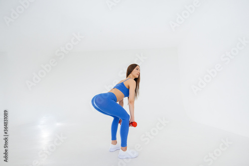 Sexy young girl performs sports exercises on a white background. Fitness, healthy lifestyle