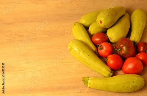 fresh natural zucchini and ripe tomatoes of different varieties from their own beds on a wooden table