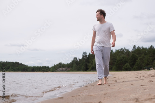 Caucasian man walking on the sandy beach looking on water © Viktor Koldunov