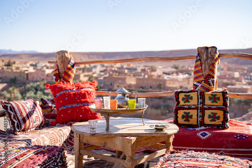 Kettle with drinking glasses in tray on wooden table at rooftop restaurant against clear sky