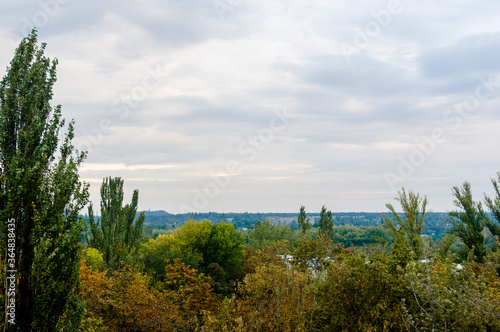 Autumn urban landscape on a Sunny day - yellow and colorful autumn trees, the sky with clouds with autumn haze