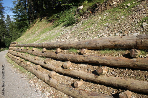 wooden log crib wall on alpine road, palificata viva ingegneria naturalistica