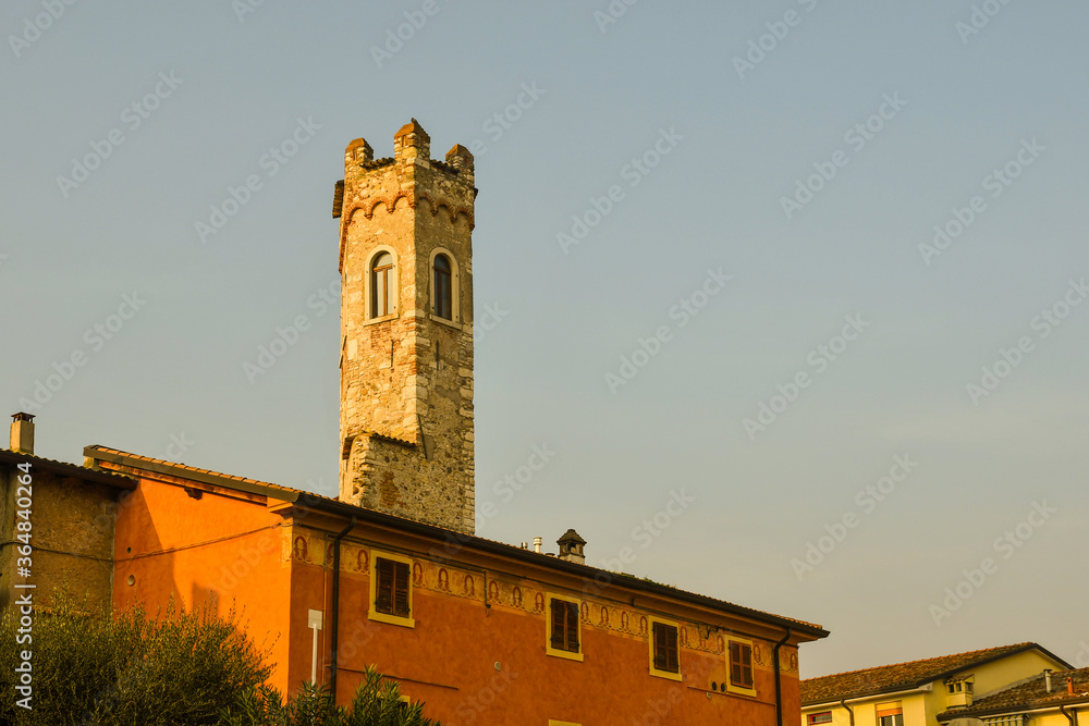 Townscape of Bardolino, an old village on the shore of Lake Garda, with the Torre Scaligera tower, the only visible remnant of the medieval castle (9th c.), against blue sky, Verona, Veneto, Italy Townscape of Bardolino, an old village on the shore of Lake Garda, with the Torre Scaligera tower, the only visible remnant of the medieval castle (9th c.), against blue sky, Verona, Veneto, Italy