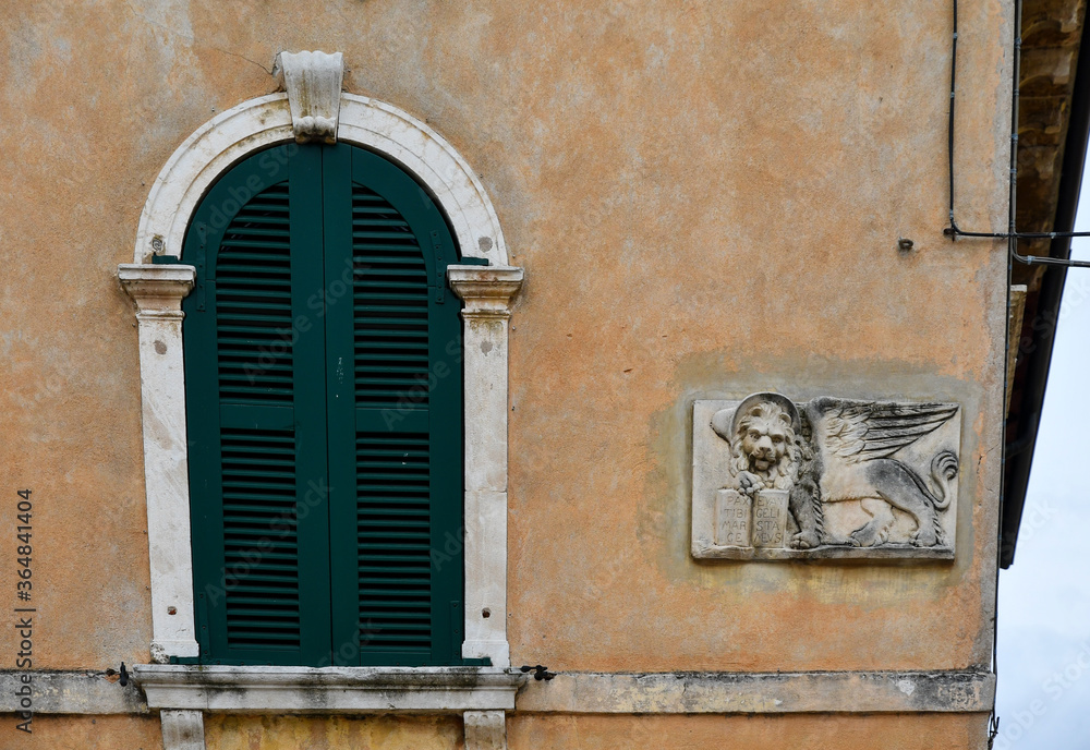 Obraz premium Exterior of an old house with an arched window and an ancient bas-relief that represents the winged Lion of Saint Mark, symbol of the city of Venice and formerly of the Venetian Republic, Italy