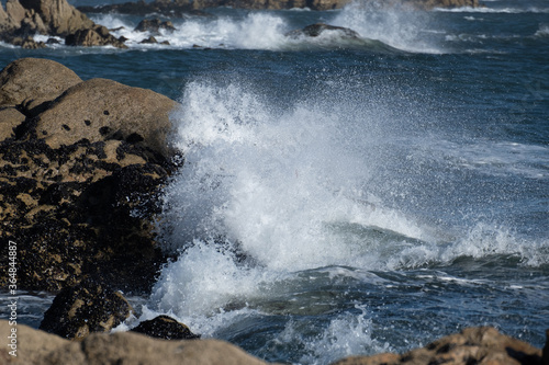 Powerful ocean waves crashing against rocks on the shore  throwing white spray into the air