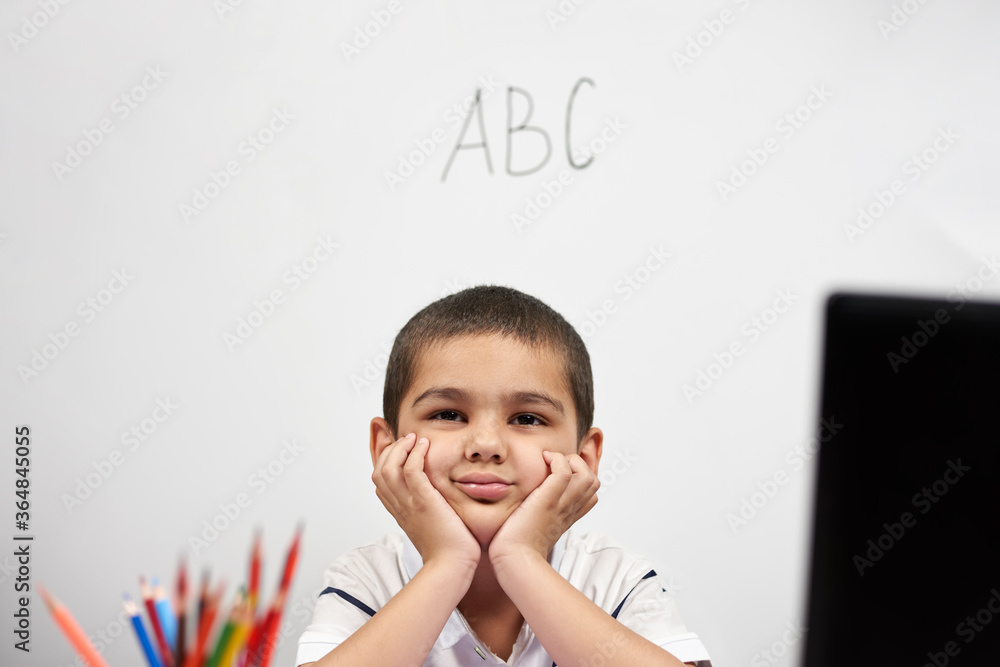 Bored schoolboy looking tired of doing homeworks. Kid trying to concentrate. Doing online classwork with laptop. Online school, homeschooling or distance education due to covid-19 Bored schoolboy looking tired of doing homeworks. Kid trying to concentrate. Doing online classwork with laptop. Online school, homeschooling or distance education due to covid-19