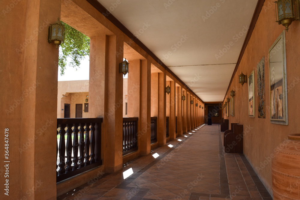 An empty long corridor lined with terracotta colored columns inside of Al Ain Museum, in the United Arab Emirates.