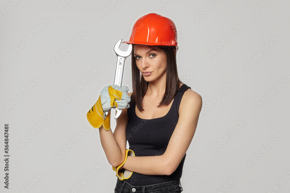 Construction girl in an orange helmet. She put it to her head. the pose shows reflection, deliberation, and some surprise..