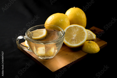 Fresh yellow lemon lime fruit with slices and fresh lemon juice on wood cutting board on black background , Copyspace for text.