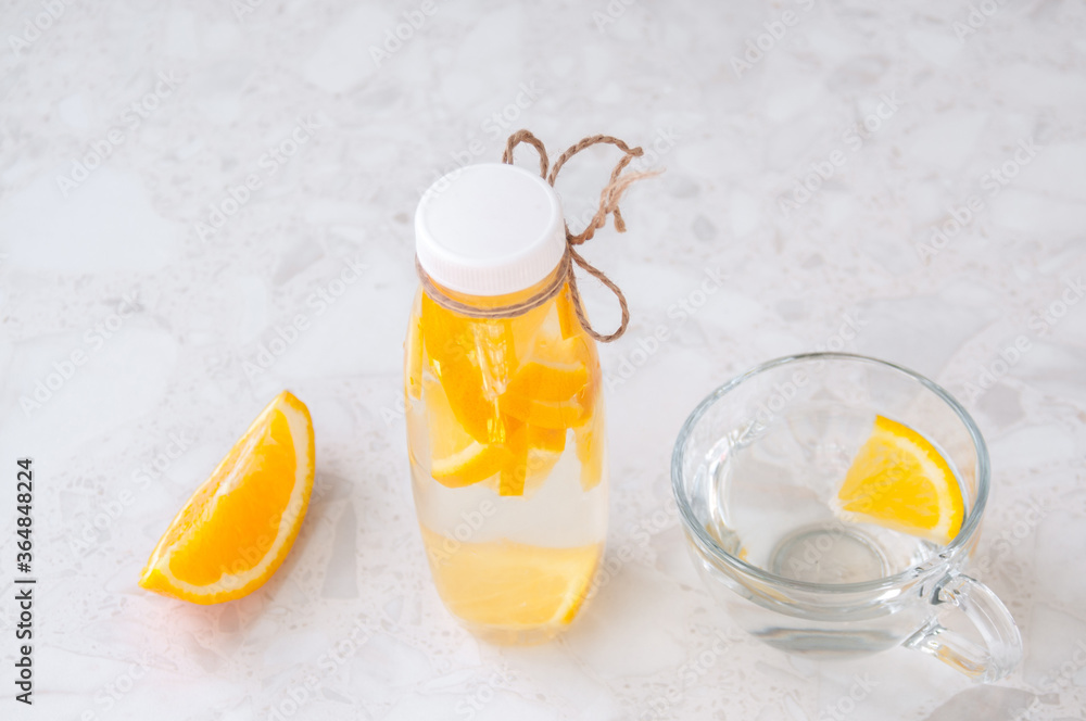 A mug of water with a slice of orange and a bottle of citrus smoothie on the table A mug of water with a slice of orange and a bottle of citrus smoothie on the table