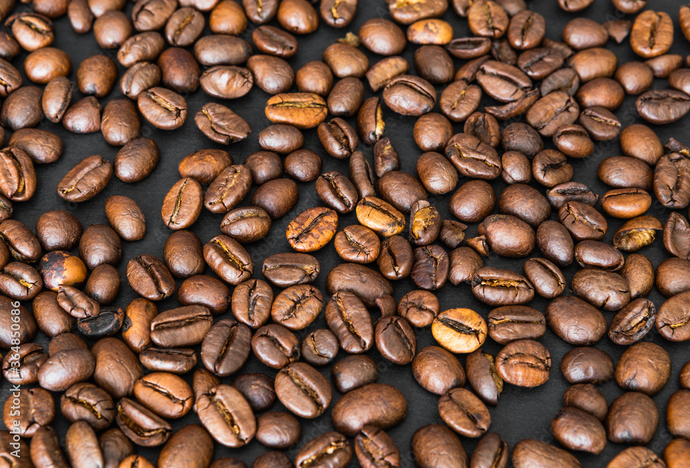 Fototapeta premium Coffee beans on a black table fill the whole space, wallpaper or background
