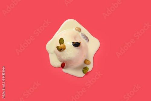 vanilla flavor ice cream starts melting with nuts on a pink background