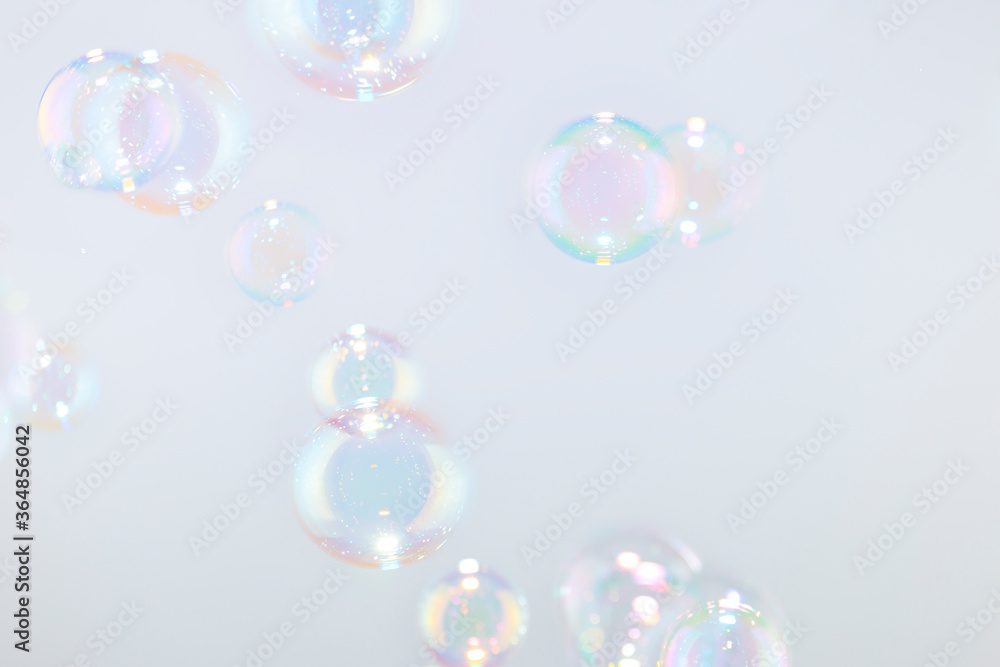 Beautiful rainbow soap bubbles float on white background.