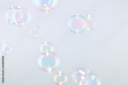 Beautiful rainbow soap bubbles float on white background.