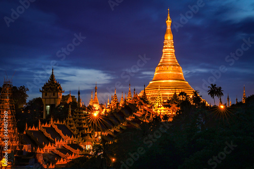 The golden Shwedagon Pagoda during blue hour twilight with dramatic sky cloud