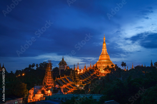 The golden Shwedagon Pagoda during blue hour twilight with dramatic sky cloud