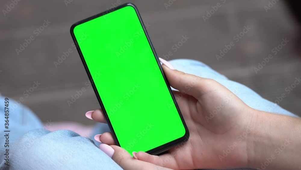 Back view of brunette holding chroma key green screen smartphone watching content Gadgets and contemporary people concept. Back view of brunette holding chroma key green screen smartphone watching content Gadgets and contemporary people concept.