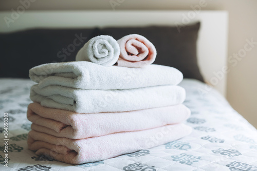 Stack of freshly launderes fluffy towels on bed in hotel