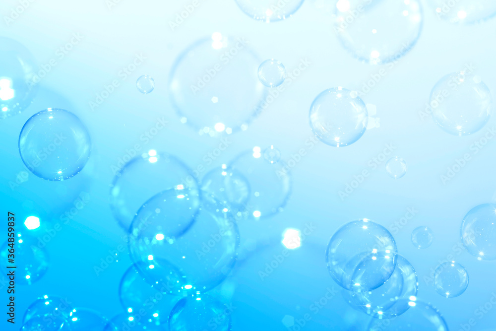 Clear soap bubbles float on a blue background. Bubbles abstract background