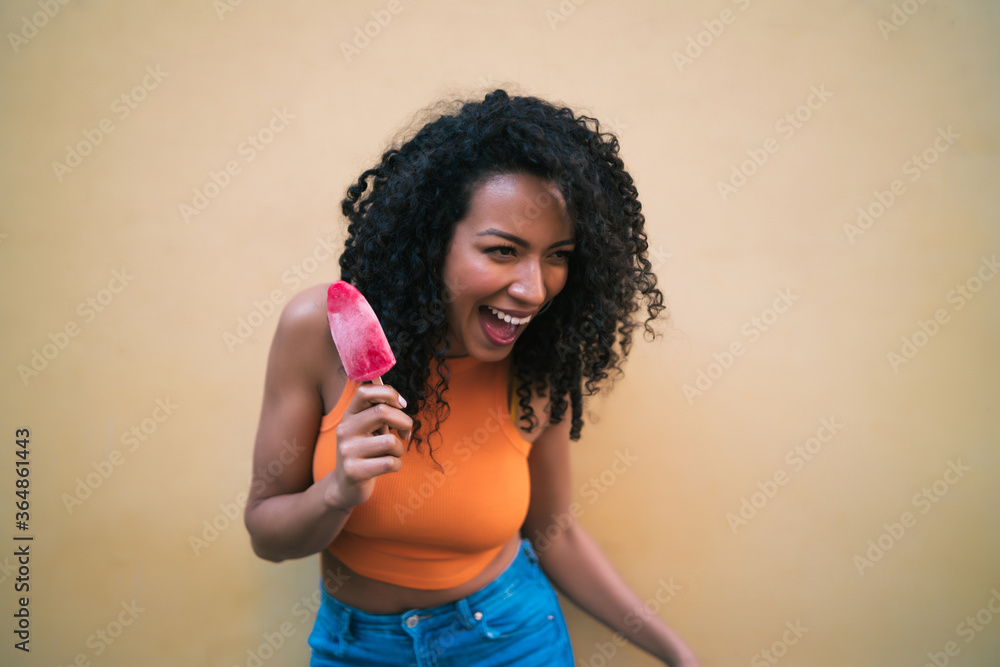 Afro woman enjoying summertime and eating an ice-cream