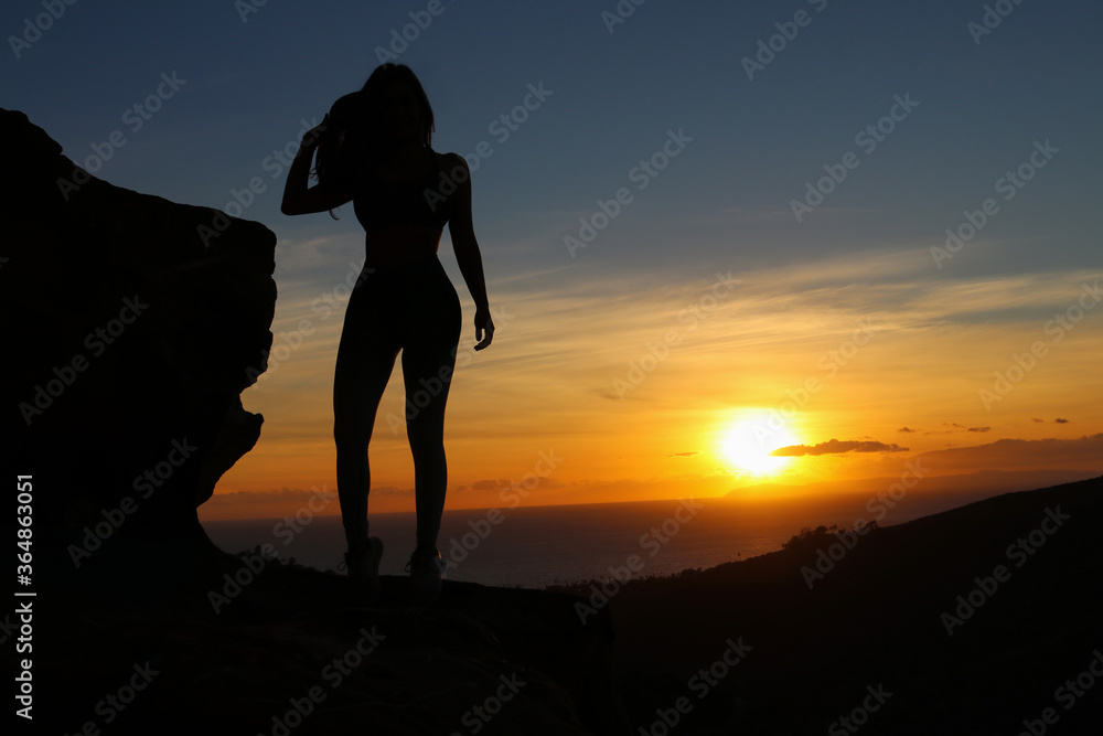 silhouette of a woman standing on a rock in front of an ocean sunset in Laguna Beach, California. 