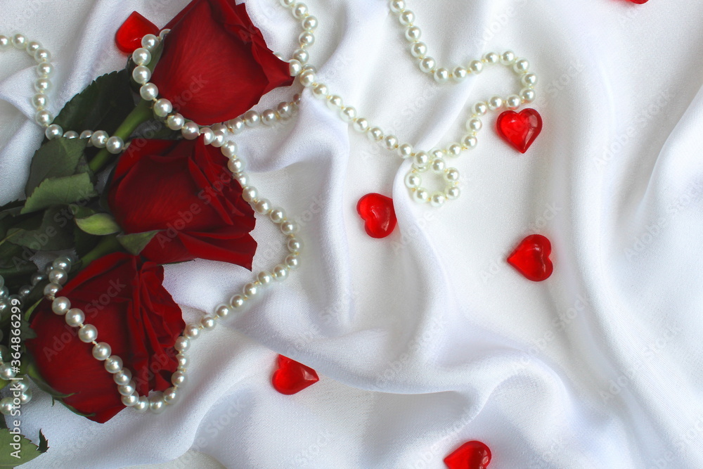 three red roses lie on a white shade from satin with hearts three red roses lie on a white shade from satin with hearts