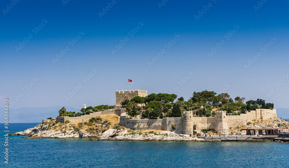 Pigeon Island (Güvercinada) view in Kusadasi, Aydin, Turkey. Historical castle in the island. The walls of the historical castle can be seen on the island. Summer and travel background.