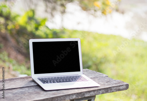 Mockup image of Laptop blank screen or graphics display montage on with workplace table, blurred nature background.