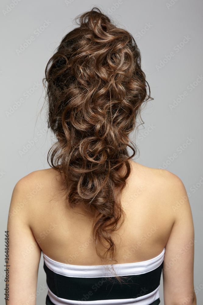 Back view portrait of beautiful young dark brunette woman on gray background. Back view portrait of beautiful young dark brunette woman on gray background.