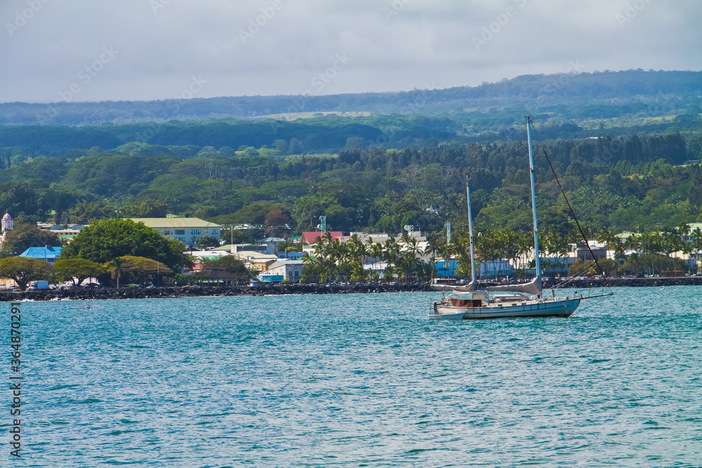 Sailboat  and Kayak Paddling in in Hilo Bay With  Downtown Hilo From The Shoreline Along Banyan Drive, Hilo, Hawaii, USA