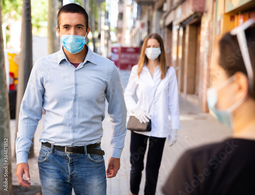 Young people in protective face mask for virus disease prevention walking on summer city street during pandemic situation