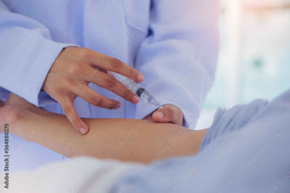 A doctor in laboratory holding a syringe with vaccines for injects coronavirus, COVID-19 vaccine at bright room in hospital A doctor in laboratory holding a syringe with vaccines for injects coronavirus, COVID-19 vaccine at bright room in hospital