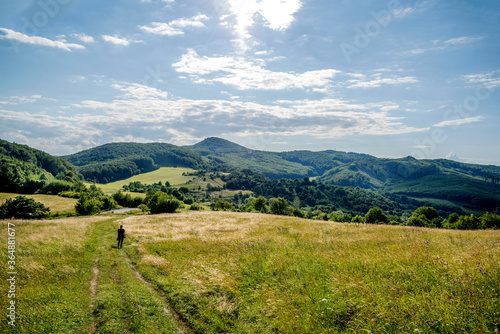 Countryside at high noon. Rural scenery with trees and fields on the rolling hills at the foot of the ridge.