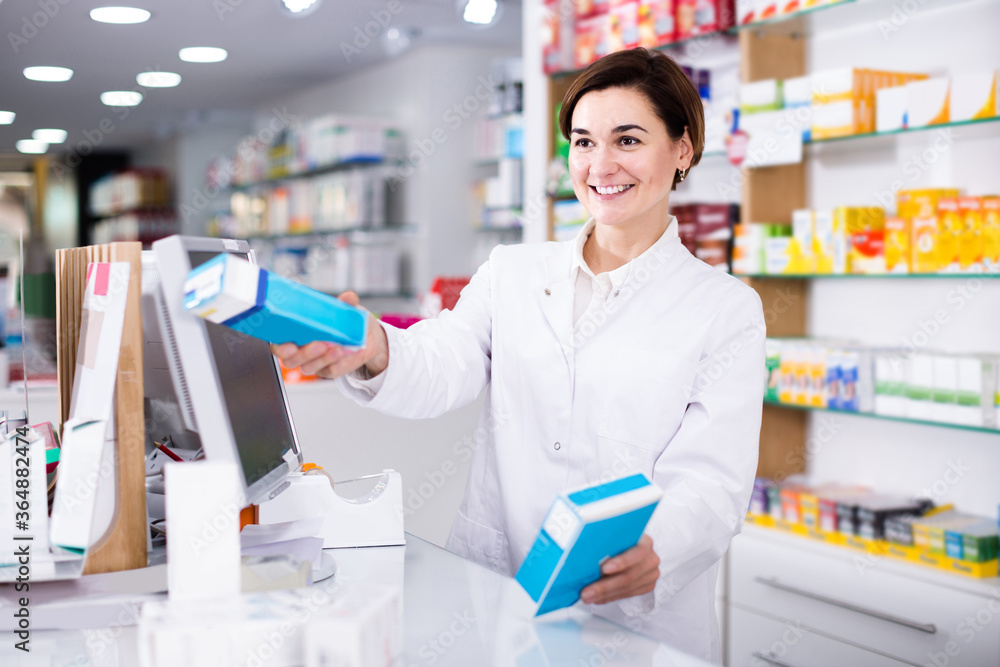 Smiling female pharmacist offering assistance at counter in pharmacy