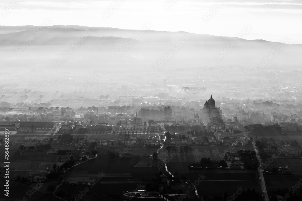 Sunset above S.Maria degli Angeli town (Assisi, Umbria, Italy) with mist and shadows