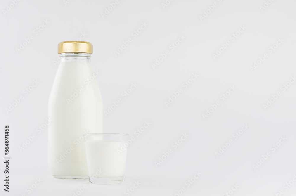 Milk, white dairy product in glass bottle mock up with glass on soft light white background, copy space. Milk, white dairy product in glass bottle mock up with glass on soft light white background, copy space.