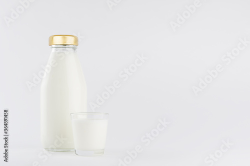 Milk, white dairy product in glass bottle mock up with glass on soft light white background, copy space.
