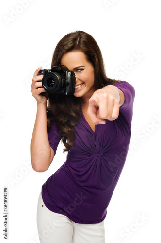 Click! Young beautiful woman photographer taking images with digital camera and pointing to camera. Isolated on white.