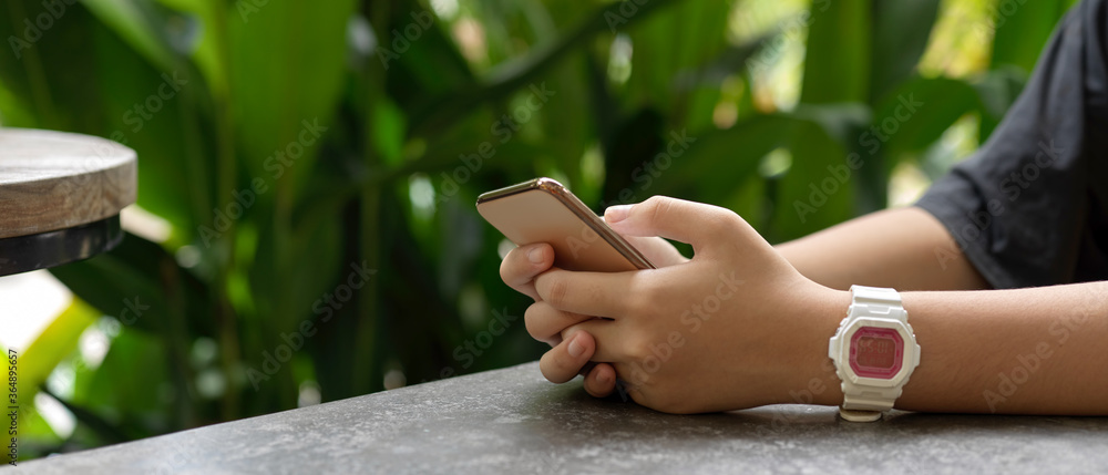 A girl using smartphone white relaxed sitting on coffee table in garden