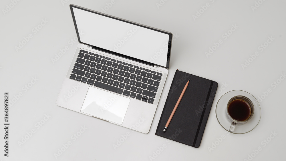 Simple workspace with mock up laptop, schedule book, pencils and coffee cup on white desk Simple workspace with mock up laptop, schedule book, pencils and coffee cup on white desk