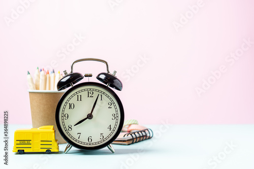 Back to school banner with black alarm clock, school bus and pencil. School supplies, other elements in pink mint empty background with copy space