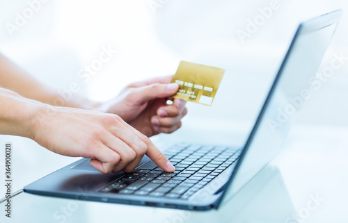 Slika na platnu Close-up of persons hands typing and paying using a laptop computer while holding a credit card