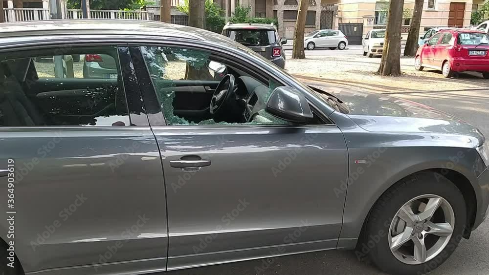 Turin,Italy.July 2020. A car has been broken into: the front right window is reduced to tiny splinters, some are on the pavement, others scattered on the dashboard. Rest of the glass is full of cracks