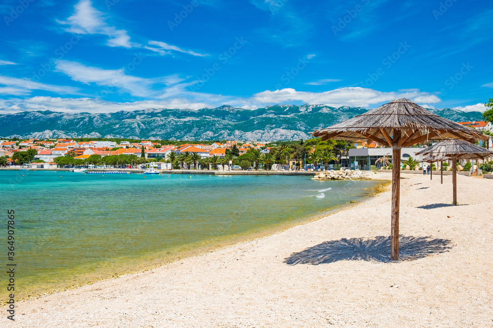 Adriatic sea shore in Croatia on Pag island, parasol on beautiful sand beach in town of Novalja
