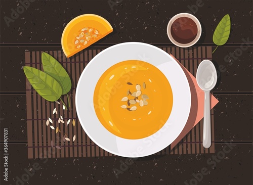 Pumpkin soup with spoon on table. Top view.