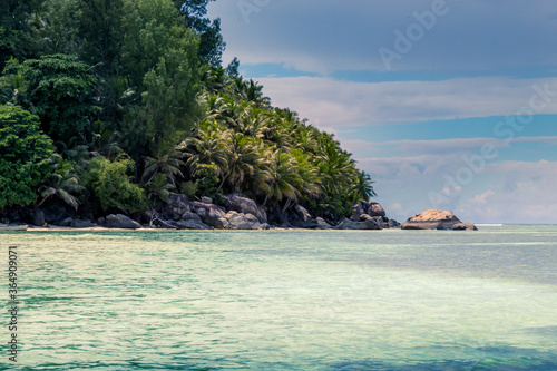 Tropical and heavenly beach with blue sky, coconut trees, white sands, crystal clear waters, surrounded by huge granite boulders rocks at seychelles islands