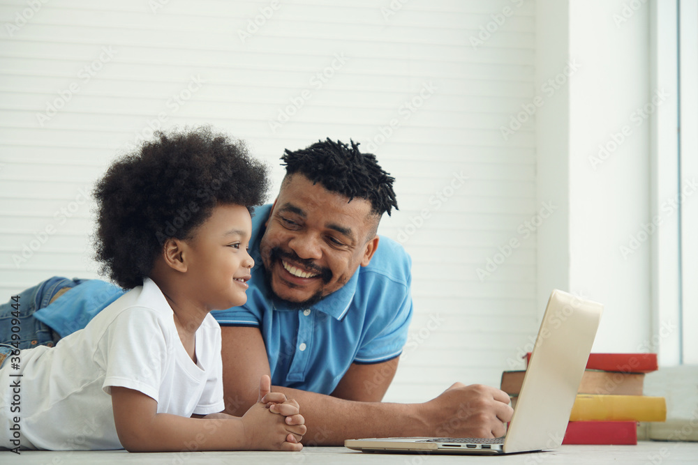 An African American family father and little son lying and smile with laptop on a white background An African American family father and little son lying and smile with laptop on a white background