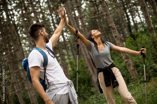 Smiling young couple walking with backpacks in the forest