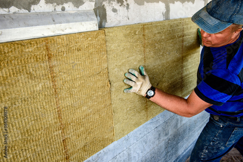 Worker insulates the house with mineral wool slabs. Internal thermal insulation of walls with mineral wool.