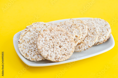 Puffed rice cakes on white dish on yellow paper background
